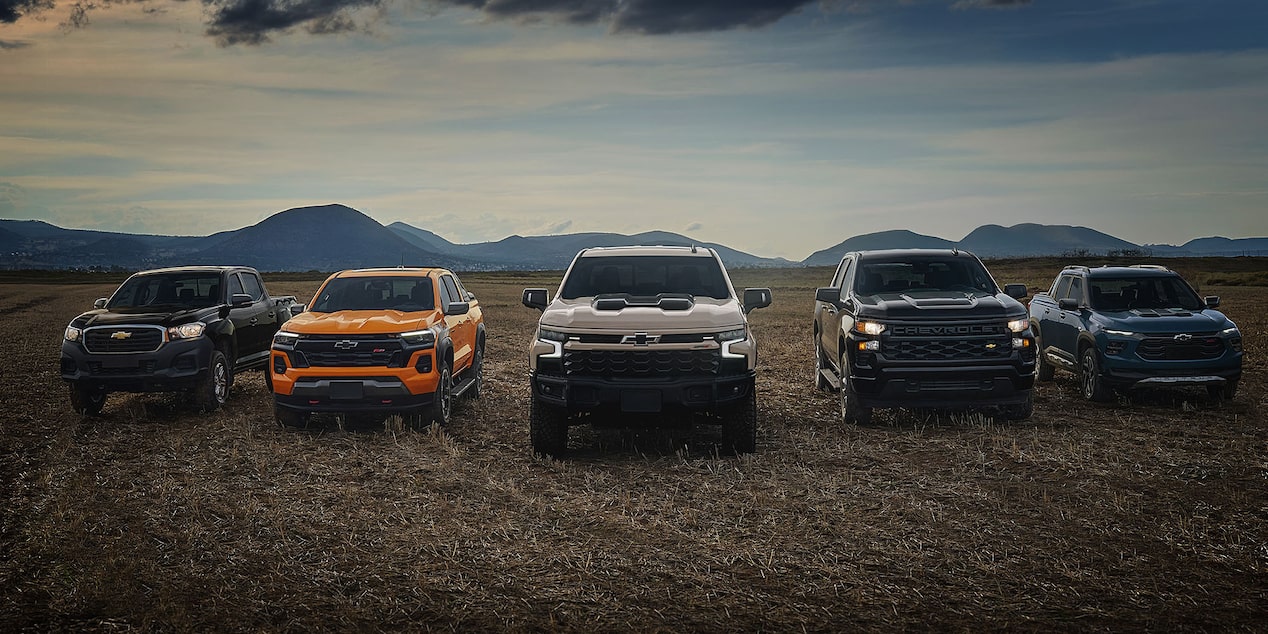 Gama de Pickups Chevrolet avanzando en un camino abierto al atardecer.