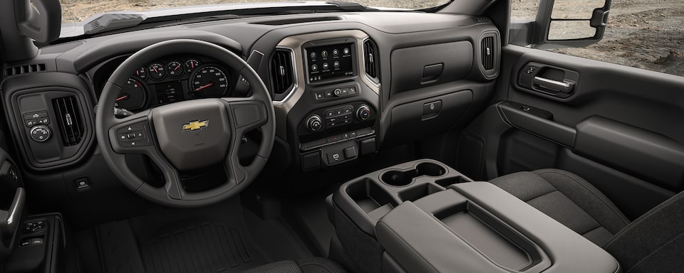 Interior de Chevrolet Silverado 3500 2021 con volante ajustable, asiento de banca y panel de instrumentos con 6 medidores